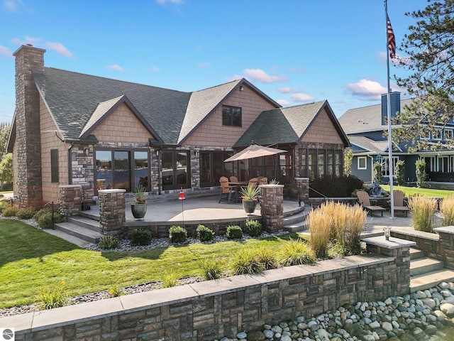 rear view of property featuring a shingled roof, a patio area, and a yard