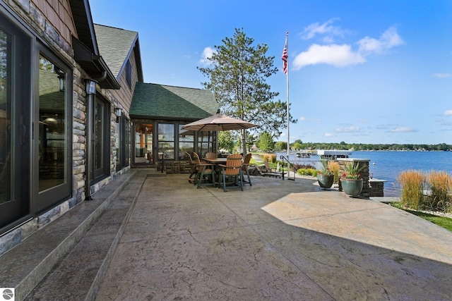 view of patio with a water view and outdoor dining space