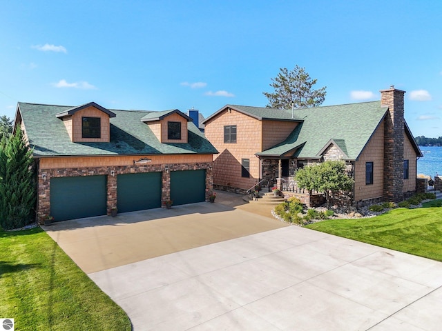 view of front of house featuring an attached garage, a shingled roof, driveway, a front lawn, and a chimney