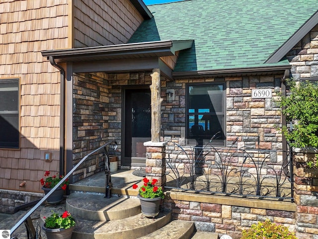 property entrance featuring stone siding and a shingled roof