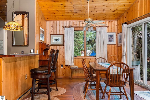 dining area with wooden walls, vaulted ceiling, and a wealth of natural light