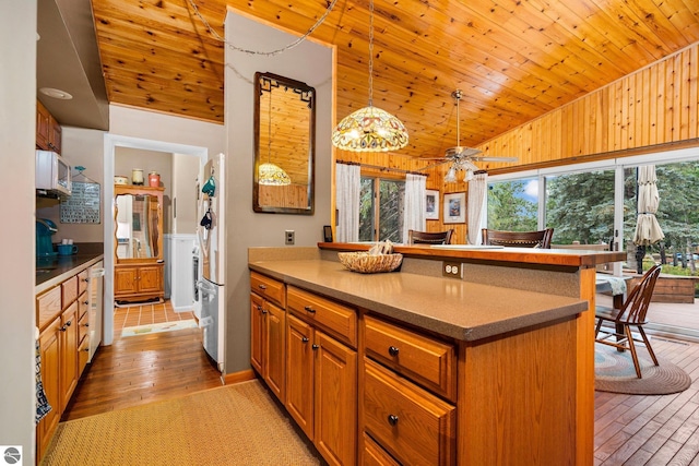 kitchen featuring a peninsula, light wood-style floors, decorative light fixtures, and brown cabinets