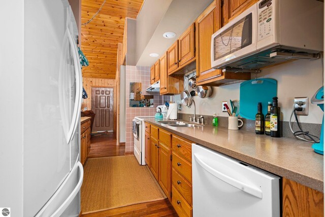 kitchen featuring wooden ceiling, brown cabinetry, dark wood-type flooring, a sink, and white appliances