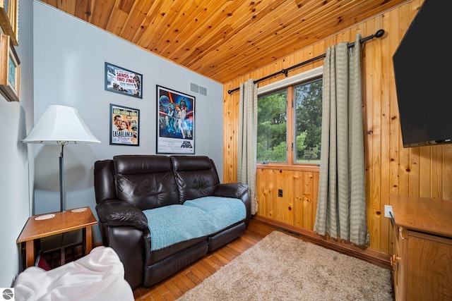 living room with wooden ceiling, visible vents, wooden walls, and light wood finished floors