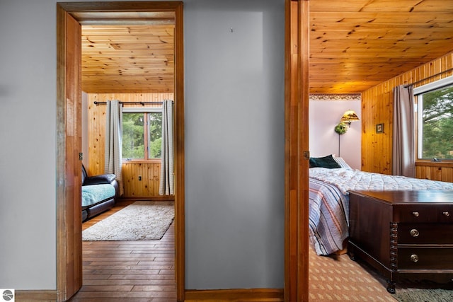 bedroom featuring light wood-type flooring, wooden ceiling, wood walls, and lofted ceiling