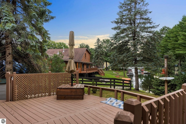 wooden deck featuring a lawn and a water view