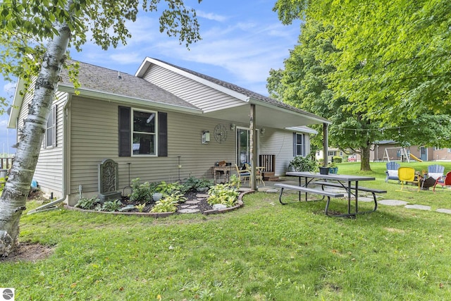 back of house featuring a patio, a lawn, and roof with shingles