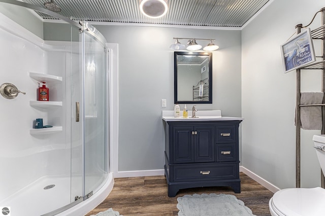 bathroom with a stall shower, baseboards, toilet, wood finished floors, and vanity