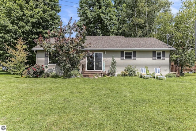ranch-style house with entry steps, roof with shingles, and a front yard