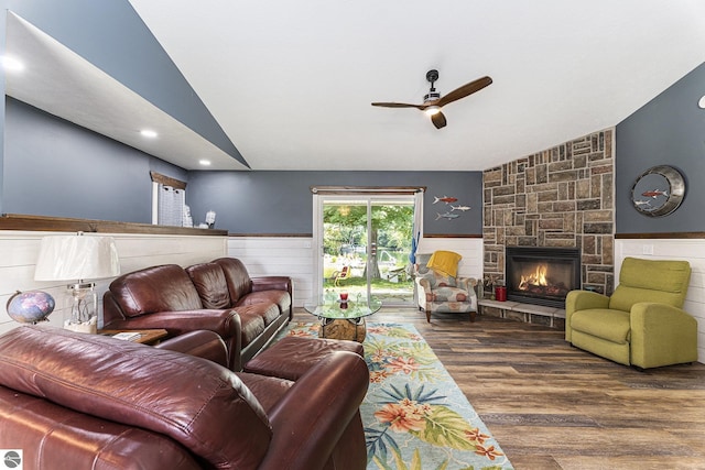 living room featuring a fireplace, lofted ceiling, dark wood-type flooring, a ceiling fan, and wainscoting