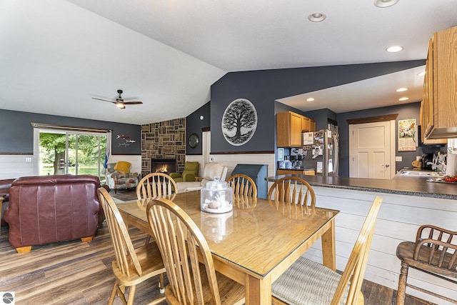 dining room with vaulted ceiling, a wainscoted wall, a fireplace, and wood finished floors