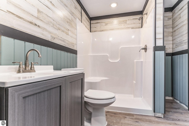 bathroom with toilet, a stall shower, wood finished floors, and vanity