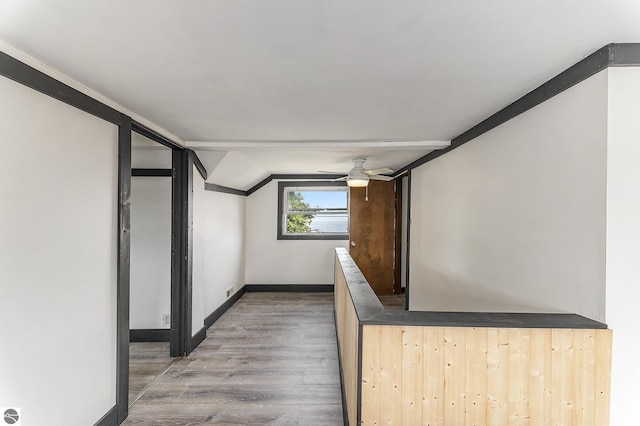 corridor featuring lofted ceiling, baseboards, and wood finished floors