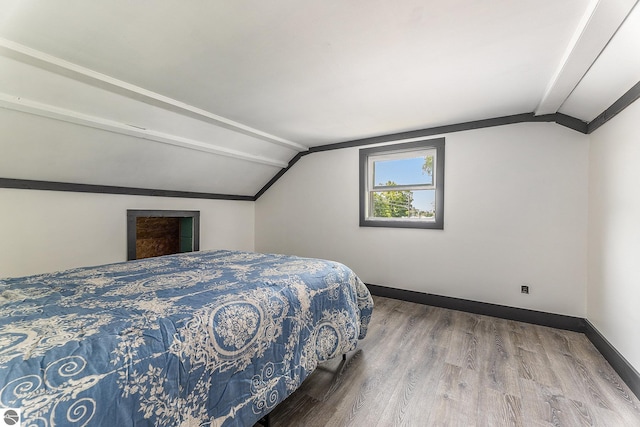 bedroom with lofted ceiling, baseboards, and wood finished floors