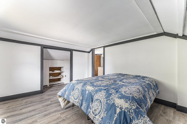 bedroom featuring vaulted ceiling, baseboards, and wood finished floors