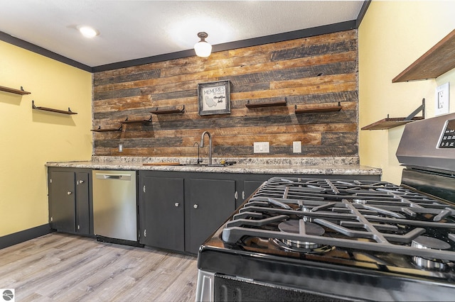 kitchen with wooden walls, stainless steel appliances, light wood-type flooring, open shelves, and a sink