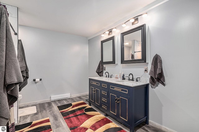 bathroom featuring double vanity, a sink, baseboards, and wood finished floors