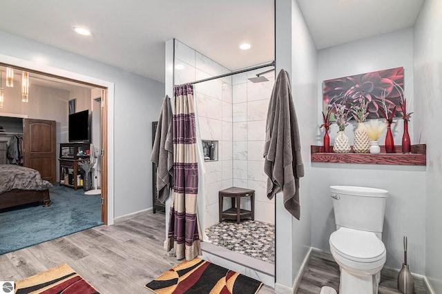ensuite bathroom featuring toilet, a stall shower, baseboards, and wood finished floors