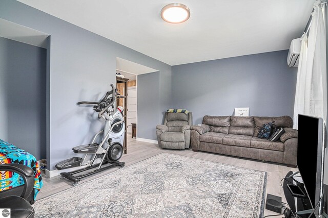 exercise area featuring baseboards, wood finished floors, and a wall mounted air conditioner
