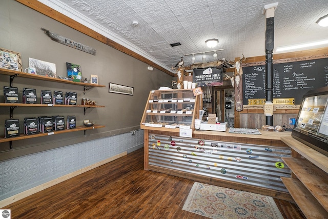 bar with wainscoting, wood finished floors, and rail lighting