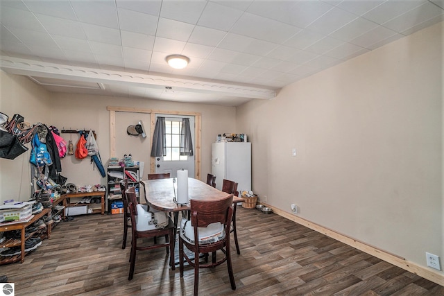 dining space featuring dark wood-type flooring and baseboards