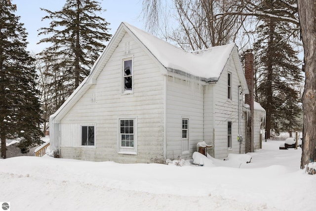 view of snow covered exterior with a chimney