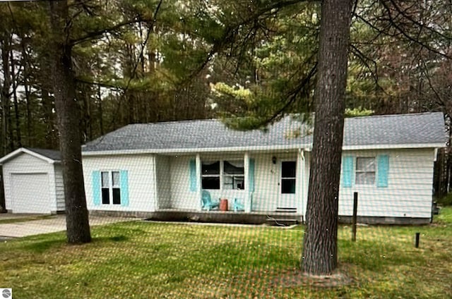 single story home featuring a garage, covered porch, a front lawn, and an outbuilding