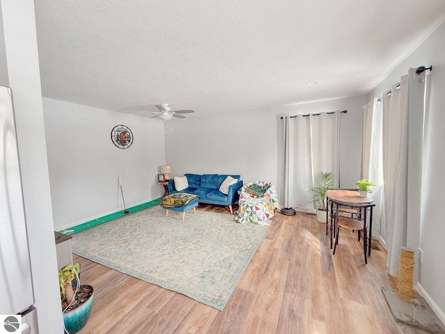 living area featuring ceiling fan, a textured ceiling, and wood finished floors