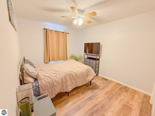 bedroom featuring a ceiling fan, wood finished floors, visible vents, and baseboards