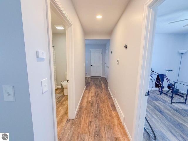 hallway featuring light wood-style floors, visible vents, and baseboards