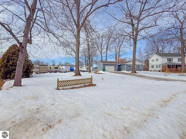 snowy yard with a garage, a residential view, and an outbuilding