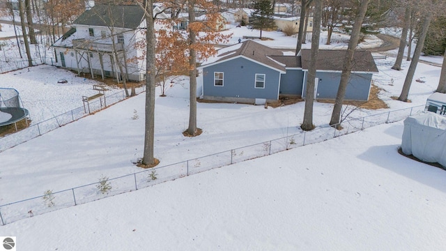 yard layered in snow with a trampoline and fence