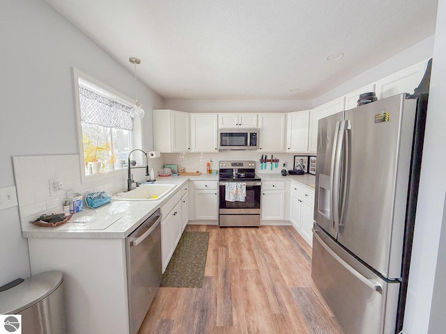 kitchen with stainless steel appliances, light wood-type flooring, a sink, and backsplash