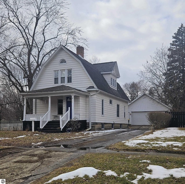 colonial inspired home with an outbuilding, a porch, a garage, fence, and a gambrel roof