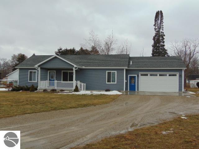 ranch-style home with covered porch, driveway, a front lawn, and a garage