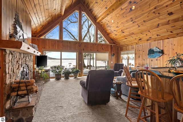 carpeted living room featuring high vaulted ceiling, wood walls, and wood ceiling