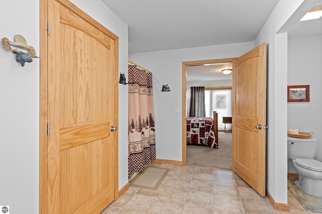 hallway with light tile patterned floors and baseboards