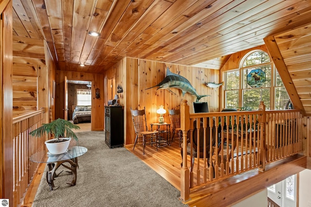 corridor with lofted ceiling, wood walls, wooden ceiling, and a healthy amount of sunlight