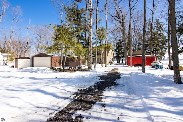 snowy yard featuring a garage and an outbuilding