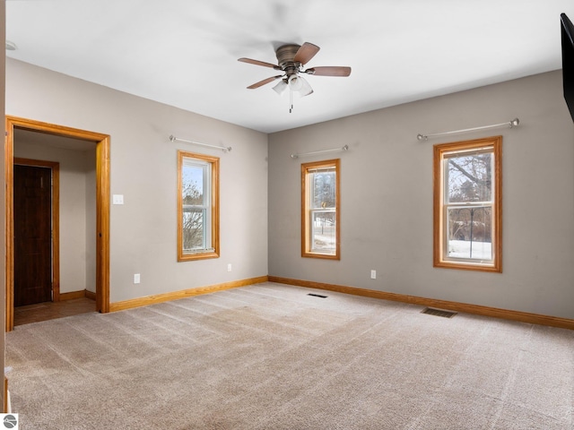 carpeted empty room with baseboards, visible vents, and ceiling fan