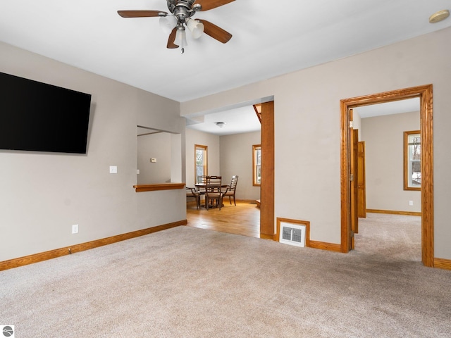 carpeted empty room with visible vents, plenty of natural light, baseboards, and ceiling fan