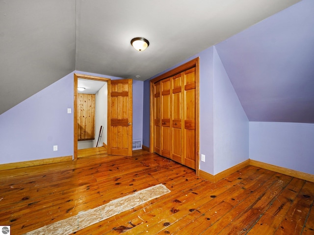 additional living space featuring lofted ceiling, hardwood / wood-style floors, and baseboards