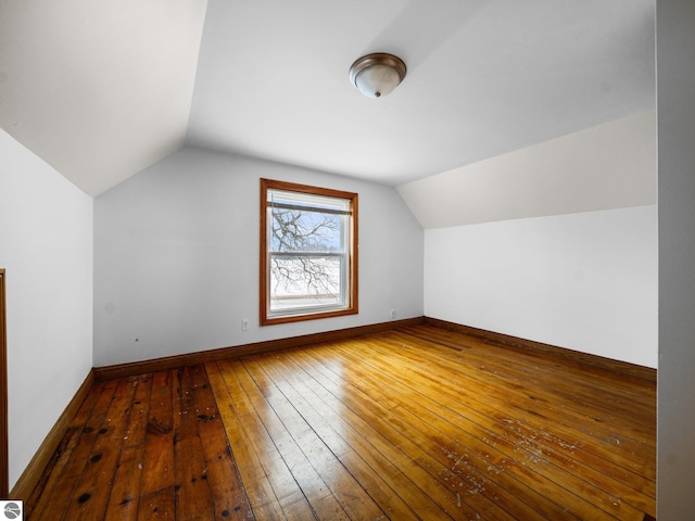 additional living space featuring wood-type flooring, baseboards, and vaulted ceiling