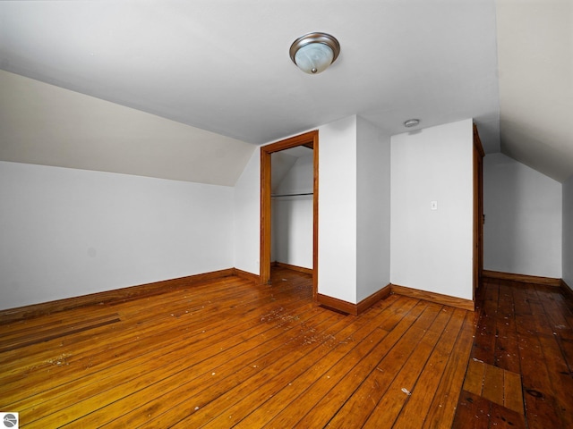 additional living space with wood-type flooring, vaulted ceiling, and baseboards