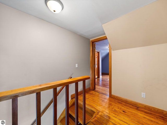 hall with baseboards, an upstairs landing, and light wood-style floors