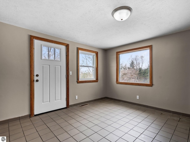 entryway featuring light tile patterned floors, a textured ceiling, visible vents, and baseboards