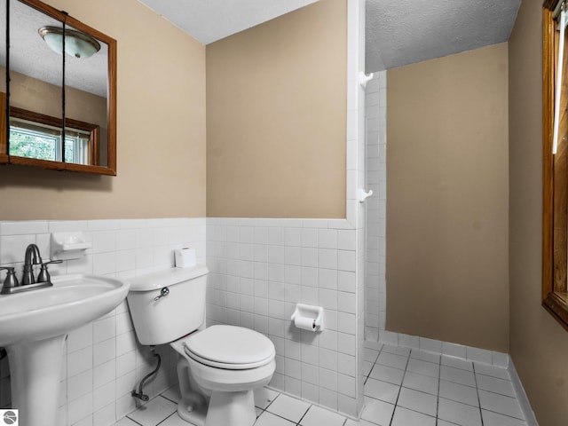 bathroom featuring toilet, tile patterned flooring, and a textured ceiling