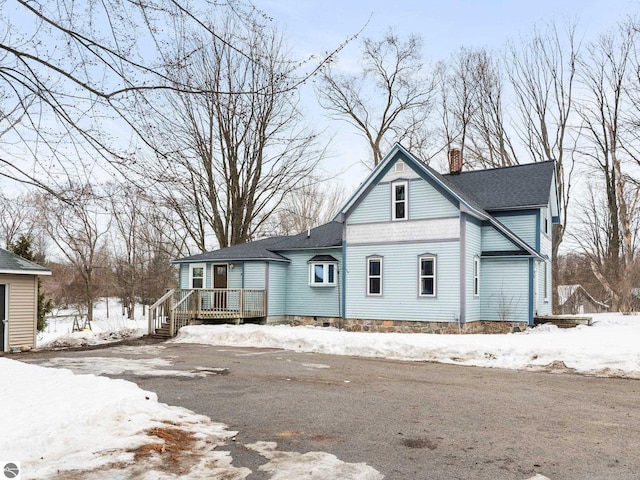 victorian-style house with a deck, a shingled roof, and a chimney