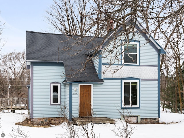 traditional-style home with a chimney and roof with shingles