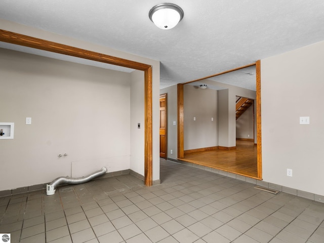 spare room featuring visible vents, a textured ceiling, and light tile patterned flooring